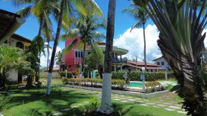 a house with palm trees and a swimming pool at POUSADA CANEDO in Guaibim