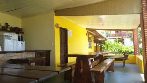 a restaurant with wooden tables and benches in a room at POUSADA CANEDO in Guaibim