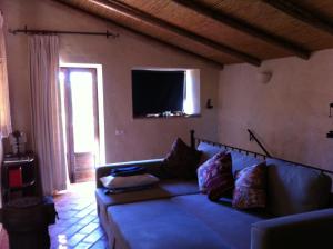 a living room with a couch and a flat screen tv at Casinha Antiga in Boliqueime