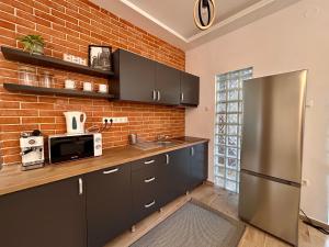 a kitchen with a stainless steel refrigerator and a brick wall at BT Apartman in Miercurea-Ciuc +41 photos