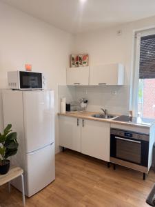 a kitchen with a white refrigerator and a sink at Escale Confort A1-2 Chambres Stationnement Facile in Roye