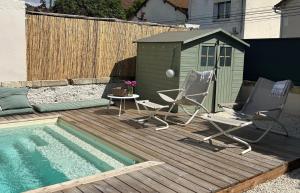 a deck with two chairs and a house and a pool at Maison Cerise in Arles