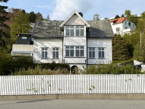 a white house with a white fence in front of it at Charming apartment with free parking close to Ålesund center in Ålesund