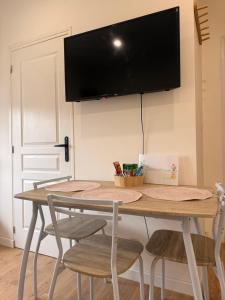 a table with chairs and a flat screen tv on a wall at Escale Confort A1-2 Chambres Stationnement Facile in Roye