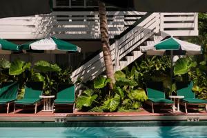 a group of chairs and umbrellas next to a pool at Perroquet Hotel in Fort Lauderdale