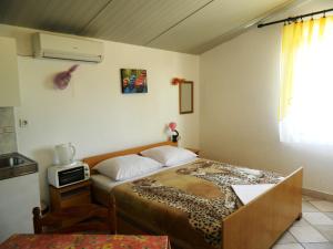 a small bedroom with a bed and a microwave at Apartment Jakoubek in Rogoznica