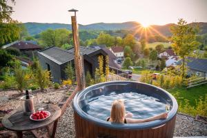 a woman sitting in a jacuzzi tub with the sunset at Ferienwohnung Weitblick im Dahner Felsenland in Bruchweiler-Bärenbach