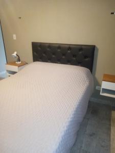 a bedroom with a white bed with a black headboard at Apart Trelew 1 in Trelew