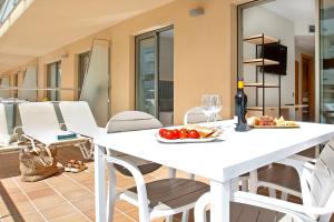 a white table with a plate of fruit and a bottle of wine at Aparthotel Odissea Park in Santa Susanna +19 photos