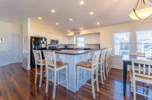a kitchen with a blue island with white chairs at Carolina Kai II - Kitty Hawk MP 3, 228 Yards to Beach, Ocean View, Pool, Hot Tub in Kitty Hawk