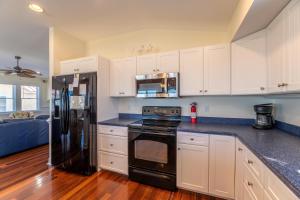 a kitchen with white cabinets and black appliances at Carolina Kai II - Kitty Hawk MP 3, 228 Yards to Beach, Ocean View, Pool, Hot Tub in Kitty Hawk +42 photos