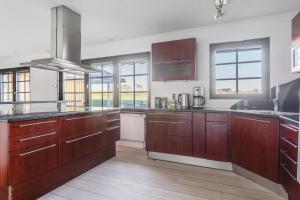 a large kitchen with wooden cabinets and windows at Gula villan in Påarp +6 photos