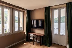 a room with a desk with a television and windows at Hotel Vapore in Torno