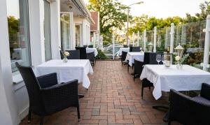 a row of tables with white table cloths on a patio at Hotel Im Schwedischen Hof in Binz