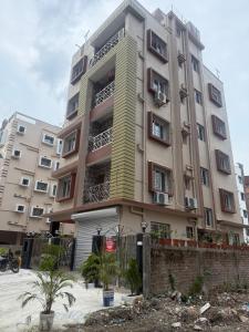 a tall apartment building in front of a building at Orchid 3BHK 3AC in New Town