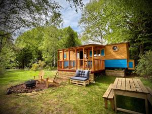 a wooden cabin with a picnic table and a grill at Domaine de Fondain in Laqueuille