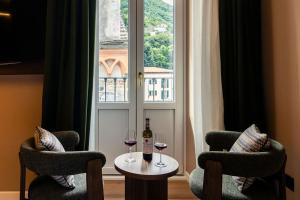 a table with two glasses of wine and two chairs at Hotel Vapore in Torno