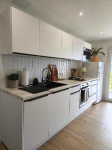 a kitchen with white cabinets and a sink at Au coucher du lac in Publier