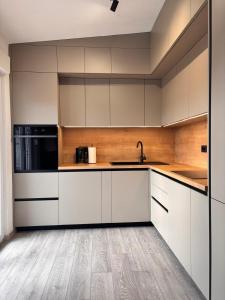 a kitchen with white cabinets and a wooden floor at Apartments Šebin in Baška Voda