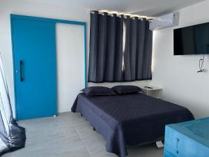 a bedroom with a bed and a blue door at Flats com Temática Grega na Praia de Aruana | Atena Flats in Aracaju +129 photos