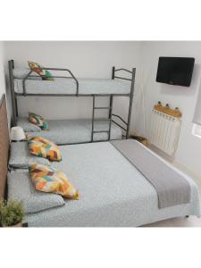 three bunk beds in a room with a tv at La Casita de Suances 1- Jardín y Parking, Ideal Familias y Mascotas in Suances