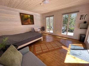 a bedroom with a bed and a couch and windows at Peaceful Forest Cabin in Nature in Paluküla