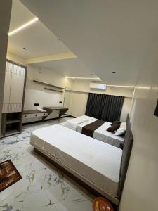 a bedroom with two beds and a desk in it at Hotel D Lite Inn in Junagadh