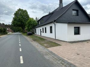 a white house with a black roof on the side of a road at Auszeit nahe Freizeitpark in Grethem