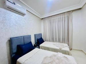 a room with two beds and a air conditioner at Appartement Climatisé 2 Chambres à Marrakech Proche Golf & Jamaâ El Fna in Marrakesh