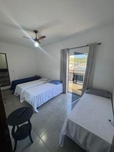 a bedroom with two beds and a table and a window at Hotel Pousa Vale Imperial in Aparecida