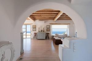 a living room with an archway and a room with the ocean at Cozy Villa in Mykonos