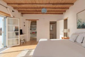 a bedroom with a white bed and a wooden ceiling at Cozy Villa in Mykonos