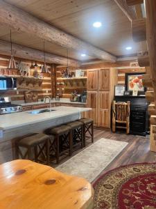 a kitchen with wooden cabinets and a large island with bar stools at Homer Spit View Cabins - The Log Cabin in Homer