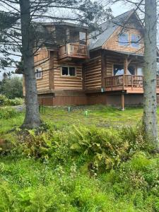 a large wooden house with a balcony and two trees at Homer Spit View Cabins - The Log Cabin in Homer
