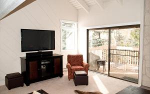 Una sala de estar con un televisor y una silla. en Snowcreek - 1503, en Sun Valley