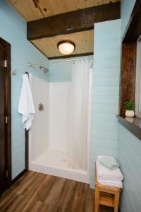 a bathroom with a shower with a white shower curtain at Homer Spit View Cabins - The Cottage in Homer +17 photos