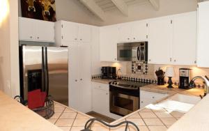 Una cocina con gabinetes blancos y un refrigerador de acero inoxidable. en Snowcreek - 1503, en Sun Valley