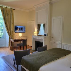 a bedroom with a bed and a desk and a fireplace at Logis des Tourelles in Cognac +55 photos