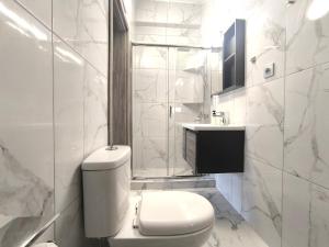a white bathroom with a toilet and a sink at Rael Apartments - free Parking in Katerini