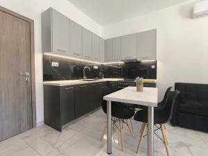 a kitchen with black cabinets and a table and chairs at Rael Apartments - free Parking in Katerini