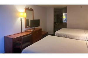 a hotel room with two beds and a desk with a television at Studio 6 Suites Louisville KY Airport/Expo Center in Louisville