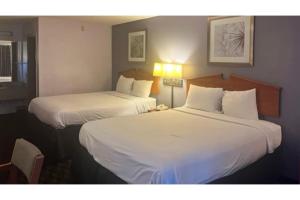 two beds in a hotel room with white sheets at Studio 6 Suites Louisville KY Airport/Expo Center in Louisville