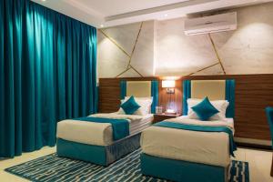 two beds in a hotel room with blue curtains at منازل الضيف in Jeddah +41 photos
