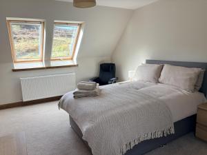 a bedroom with a large bed and two windows at Abernethys Cottage in Connel