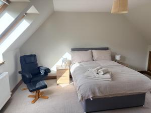 a bedroom with a bed and a blue chair at Abernethys Cottage in Connel