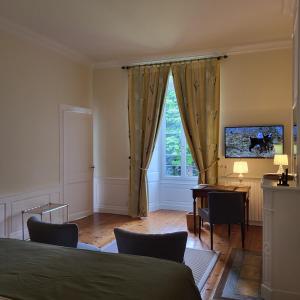 a bedroom with a bed and a desk and a window at Logis des Tourelles in Cognac