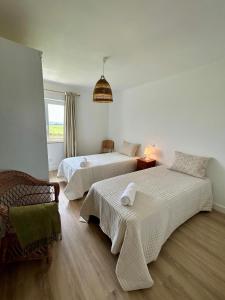 a bedroom with two beds and a chair and a window at Sol Dorado in Ferrero