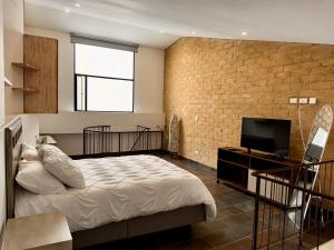 a bedroom with a bed and a tv and a brick wall at Apartamentos Chia in Chía