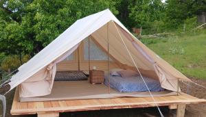 a tent with a bed on a wooden platform at Camping à la Ferme de la Marette in Gluiras
