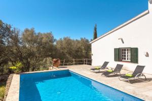 a swimming pool in front of a house with chairs at Finca Ses Curtanetas by 3VILLAS in Alaior